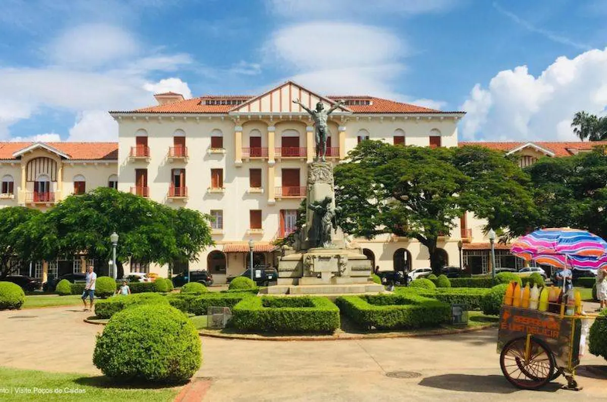 Fachada imponente do Palace Hotel com jardins simétricos e estátua ao centro em Poços de Caldas.